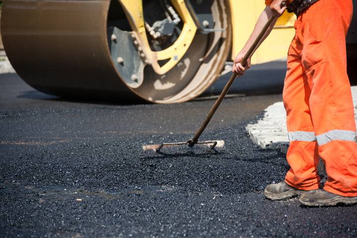 pracownicy wylewający asfalt